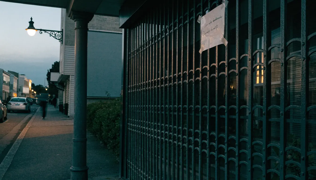 A closed New Zealand shopfront with a blank billboard under a streetlamp at dusk